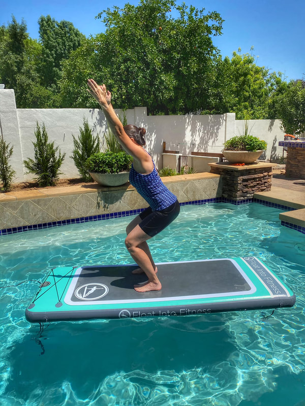 Picture of female on yoga board in a pool doing a yoga pose.